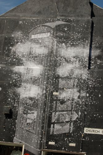 Painting of an exploding telephone box on the site of a building.