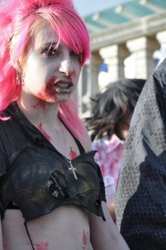 Thin woman with pink hair and a black crop top dressed as a zombie
